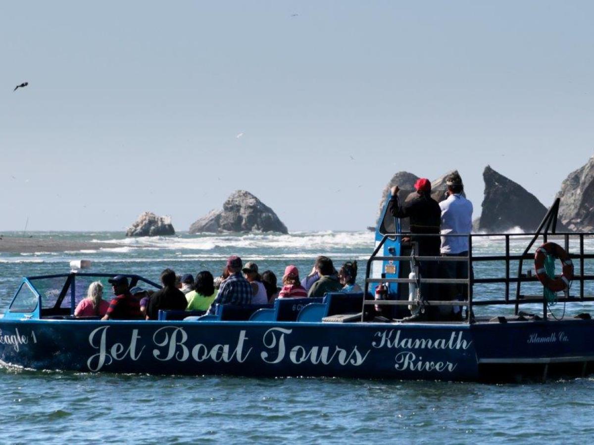 Blue jet boat filled with passengers looking down the river